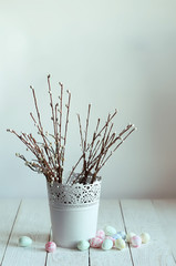 Still life with willow branches in vase and easter eggs on table, abstract light background. symbol of spring season, Palm Sunday, Easter. festive composition in minimal style