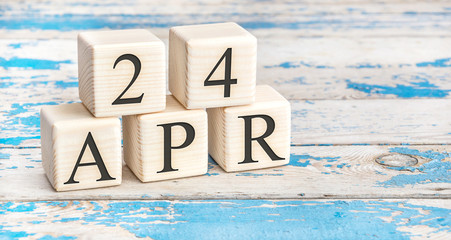 April 24th. Wooden cubes with date of 24 April  on old blue wooden background.