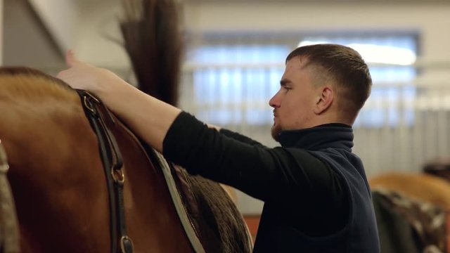 Man carrying horses saddle. Putting saddle on horse. Man put saddle on his horse for riding.