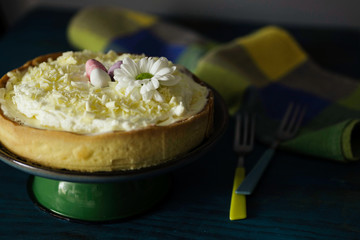 Lemon tart with whipped cream, decorated with chocolate eggs and a flower. 
