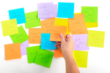 To do list - multicolored task notes with hadnd choosing one on white background