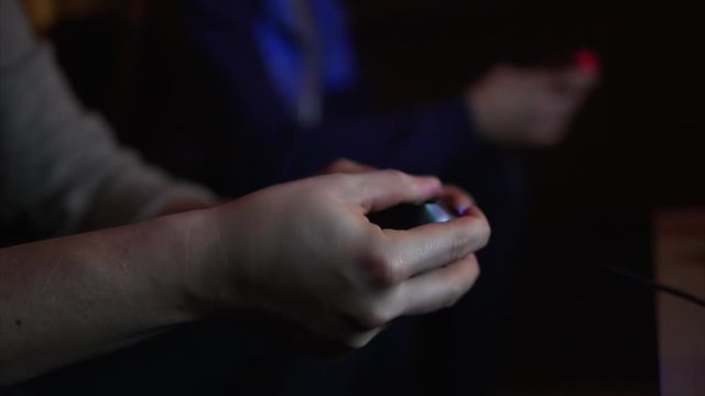 Close up shot of man's hands quickly clicks on the joystick of video game.