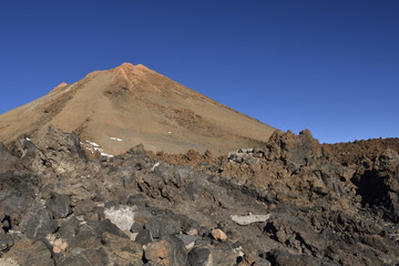 Teide top with lava stone in foreground and against a blue sky