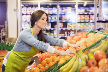 Saleswoman Arranging Oranges In Supermarket