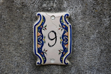 Numéro 9 peint sur une plaque en céramique.