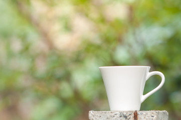 Coffee mug with blurry nature background.