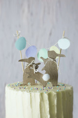 Close up of Easter themed wedding or birthday cake, with paper rabbit silhouettes as cake topper. 
