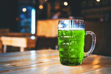 Glass of fresh cold green beer on a wooden bar counter in pub with free space for your text. Beautiful background of the Oktoberfest and St. Patrick's day. fine grain. Soft focus. Shallow DOF