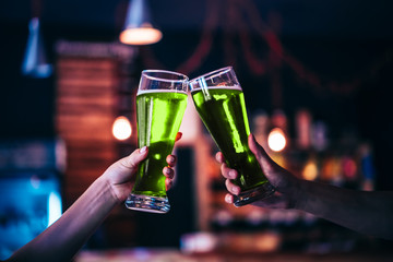 Two friends toasting with glasses of green beer at the pub with free space for your text. Beautiful background of the Oktoberfest and St. Patrick's day. fine grain. Soft focus. Shallow DOF