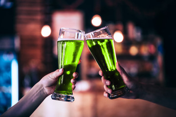 Two friends toasting with glasses of green beer at the pub with free space for your text. Beautiful...