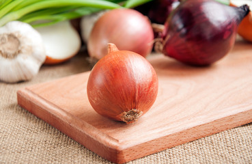  Various onions on a board on a background sacking, burlap