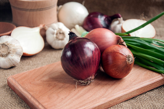 Various onions on a board on a background sacking, burlap