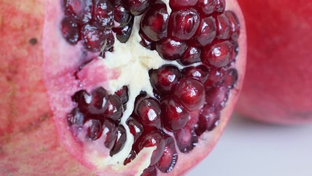 Opened Lythraceae family pomegranate fruit with seeds 4K 3840X2160 UHD tilting video - Halved red healthy Punica granatum close-up slow tilt 2160p UltraHD footage 
