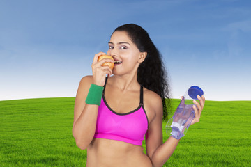 Fototapeta premium Young woman eats apple in meadow