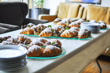 Assortment of fresh pastry on table in buffet. Croissants and cakes