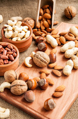 Almonds, cashew, walnuts and hazelnuts in wooden bowls on wooden and burlap, sack background