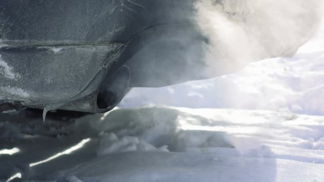 Car pipe puffs out exhaust gas clouds. Smoke clouds coming out of automobile tailpipe. Air and environment pollution by vehicle closeup shot.