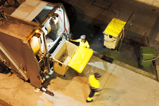garbage collector truck vehicle with municipality workers  in  street  city at night