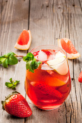 Traditional summer drink pink sangria. With wine, strawberries, oranges, lemon, green apple and grapefruit. On a wooden rustic table, copy space