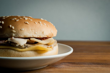 hamburger on wood table with copy space and white wall background.