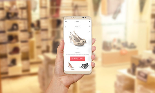 Woman buy shoes online with modern mobile app. Shoe store in background.