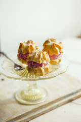 Strawberry cream puffs on a cake plate, served with tea. Shallow depth of field.