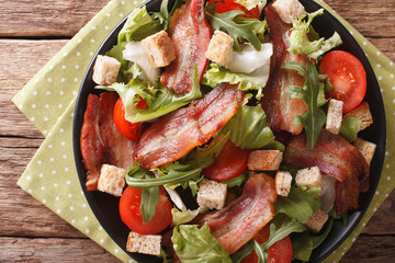 Mix salad of fried bacon, tomato, croutons and lettuce close-up. horizontal top view