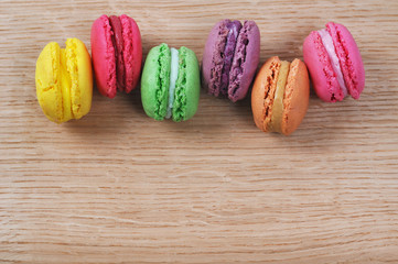 Different types of tasty and colorful macaroons on wooden table with copyspace