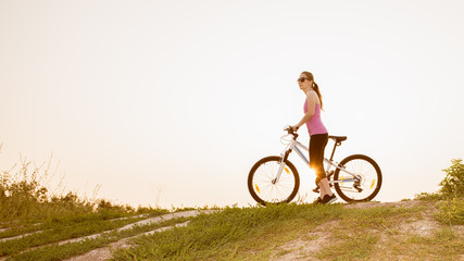 Fototapeta premium Girl on mountain bike rides on the trail on a beautiful sunrise.