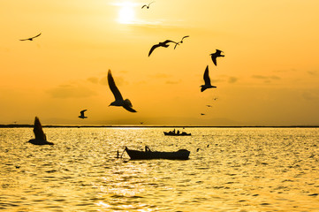 Naklejka premium Fishing boat on the sea at sunset. Seagulls flying on the sea.