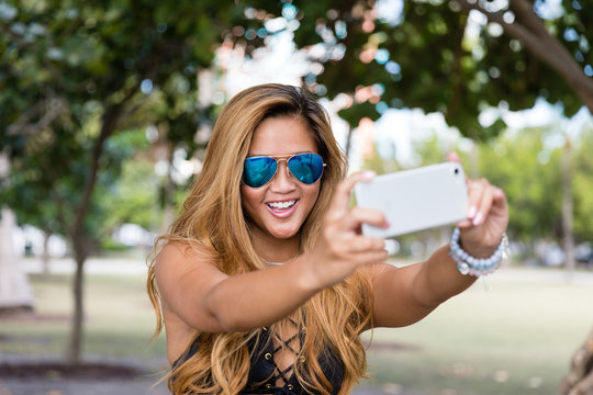 Selfie fun millennial woman with blue sunglasses taking picture. Summer holiday girl happy at smartphone camera taking self-portrait on her travel vacations