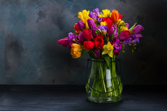 bouquet of bright spring flowers in vase on black background