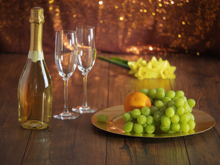 Still-life: Champagne bottle, grapes, glasses, daffodils.
