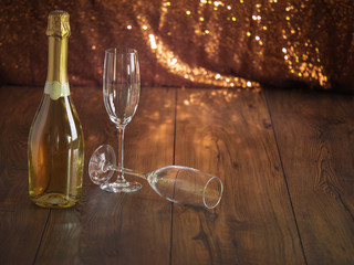 Unmarked Champagne bottle on a wooden surface and glitter background.
