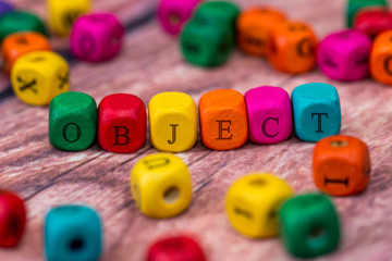 object - word created with colored wooden cubes on desk.