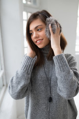 Teen girl with fluffy headphones listen music in white room