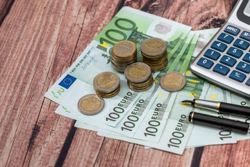 100 euros bills with ink pen, coin and calculator.
