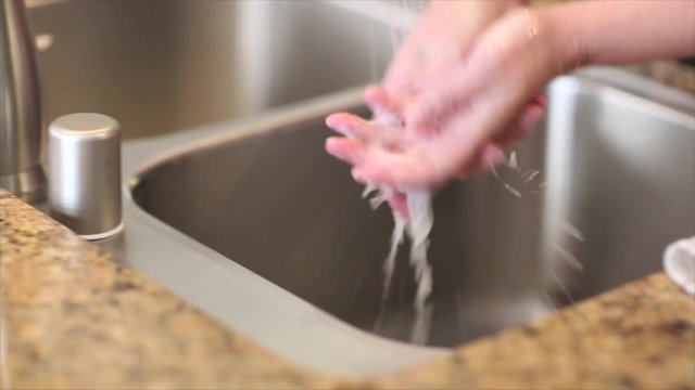 Pan of Woman Washing Her Hands in a Stainless Steel Sink