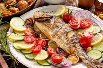Grilled fish with roasted potatoes and vegetables on the plate