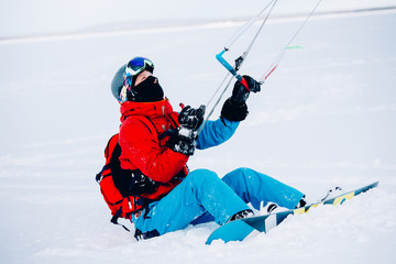 Fototapeta na wymiar Snowkiting. Male athlete snowboarder rides a kite skiing on a frozen lake. The Kola Peninsula. kiting. Snowkite