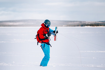 Fototapeta na wymiar Snowkiting. A snowboarder athlete collects packs on a kite rink over a frozen lake. The Kola Peninsula. Kitesurfing. Snowkite.