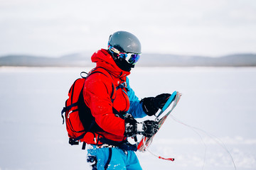 Snowkiting. A snowboarder athlete collects packs on a kite rink over a frozen lake. The Kola...
