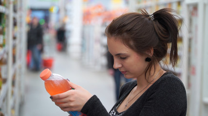 woman buys juice in supermarket or store.