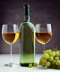 Bottle of white wine, grape on wooden table