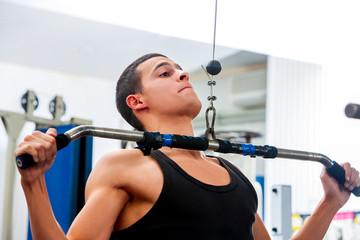 Man pulling on bar in gym. Top view of sportsman pull ups exercising in fitness center.