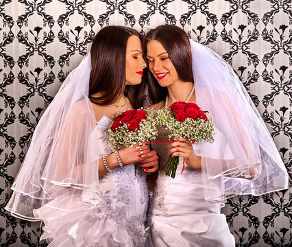 Lesbian couples in wedding bridal dress kissing . same-sex marriage and love couple with flower bunch. Home wallpaper background.