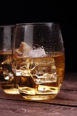 glass of whiskey with ice on a wooden