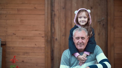 Granddaughter standing behind grandfather and hugs old man and smile. Girl bands and male kiss her hand. 4K