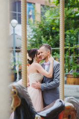 Obraz na płótnie Canvas Happy newlyweds kiss near the carousel