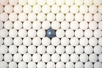 Black bulb among many white ones. Background of airsoft balls
